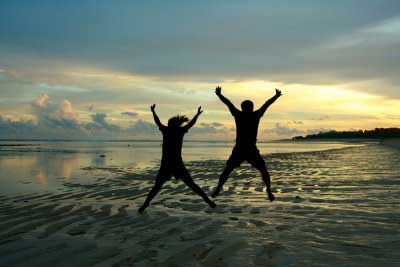Young girl an boy jumping on the sea shore